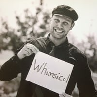 Man holding a piece of paper that says Whimiscal.